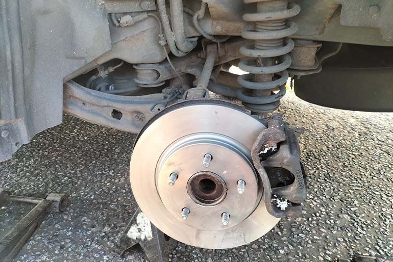 Brake disc and calliper exposed on a wheel hub during a repair carried out on a customer's driveway